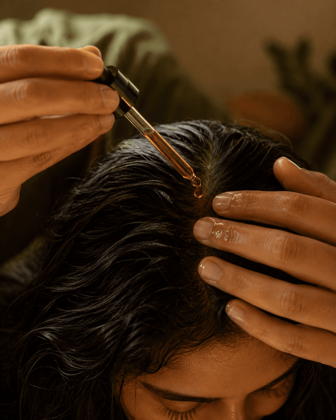 Hands applying RUVS Naturals Hibiscus Hair Oil in a warm home ritual